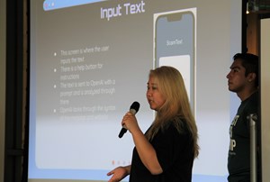Student holding microphone in front of screen and presenting